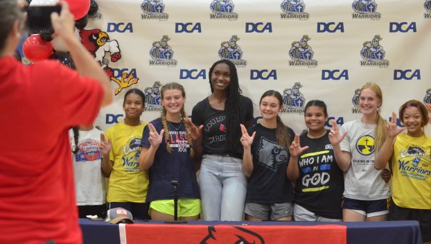 Grace Mbugua, center, and her Danville Christian teammates give the “L’s up” sign as they pose for a photo Tuesday during a signing ceremony celebrating her commitment to play basketball for Louisville.
