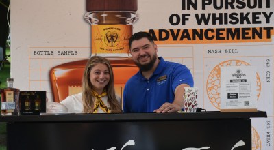 Haley Perros and Noah Baker greet attendees while working the Wilderness Trail Distillery booth during the Great American Brass Band Festival in Danville on Saturday, May 31, 2025. (Photo by Casey Roberts)