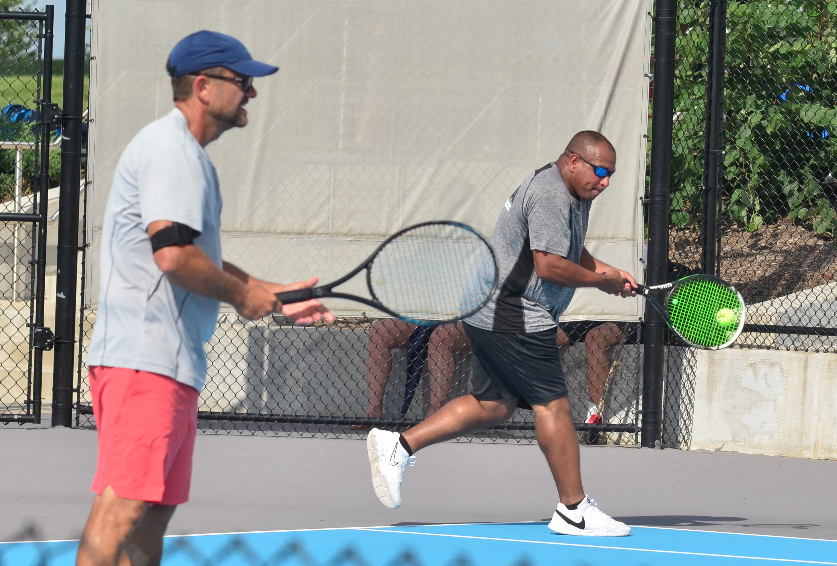 Greg Foley, right, plays a shot as Tao Costello stands at the ready Sunday during the men’s 40-and-over doubles final at the Danville Open. (Photo by Mike Marsee)