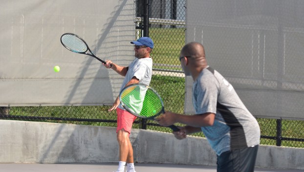 Tao Costello, left, returns a shot as Greg Foley looks on Sunday during the men’s 40-and-over doubles final at the Danville Open. (Photo by Mike Marsee)